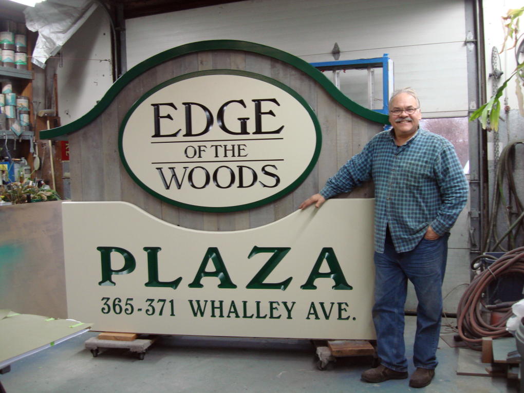 John Miller in front of top half of sign for Edge of the Woods in New Haven